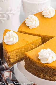 a pumpkin cheesecake with whipped cream on top is sitting on a cake platter