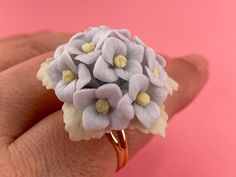 a woman's hand holding a ring with white flowers on the front and yellow center