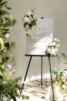 an easel with flowers and greenery on it