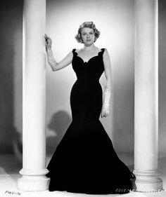 an old black and white photo of a woman in a long dress standing next to columns