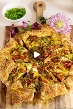 a pizza sitting on top of a wooden cutting board next to a bowl of vegetables