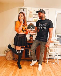 a man standing next to a woman in a living room holding a pumpkin shaped object