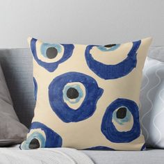 a blue and white pillow with an evil eye pattern on it sitting on a couch