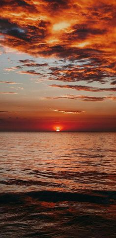 the sun is setting over the ocean with clouds