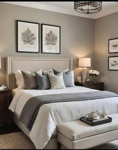 a bedroom with gray walls and white bedding, two framed pictures on the wall