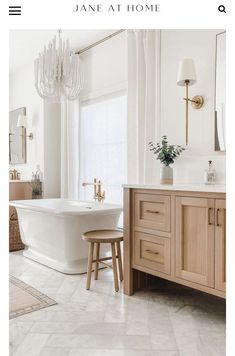 a white bath tub sitting under a chandelier in a bathroom