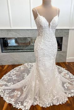 a wedding dress on display in front of a fireplace