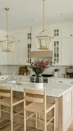 a large kitchen with white cabinets and wooden chairs in the center island, two pendant lights hanging from the ceiling