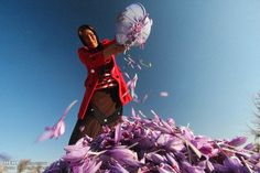 a woman standing on top of a pile of purple flowers