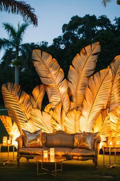 a couch sitting on top of a lush green field covered in lots of lit candles