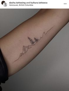 a person with a tattoo on their arm that has mountains and trees in the background