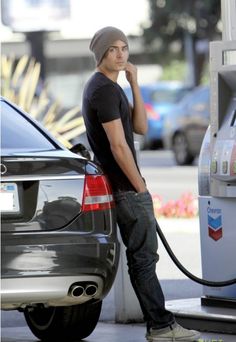 a man standing next to a gas pump with his head in his hands and looking up