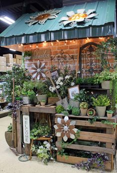 an assortment of potted plants on display in front of a building with lights and signs