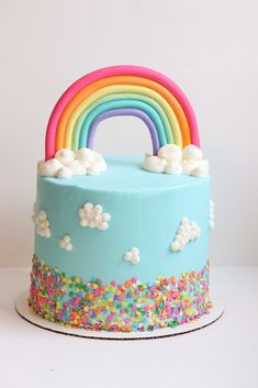 a rainbow cake with sprinkles and white frosting on the top is shown