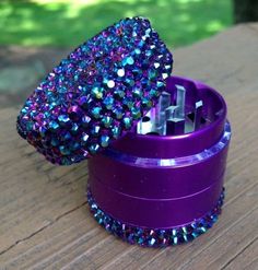 an open purple container with colorful beads on it sitting on a wooden table next to a tree