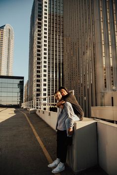 two people standing next to each other in front of tall buildings with skyscrapers behind them