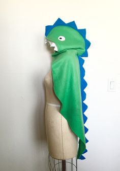 a mannequin with a green and blue scarf on it's head next to a white wall