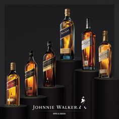 several bottles of different types of alcohol on black pedestals with white lettering that reads, johnie walker