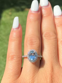 a woman's hand with a ring on it and an oval blue topaz