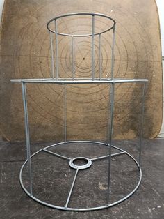 a metal stand with a circular design on the top and bottom, in front of a brown background