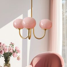 a pink chair sitting in front of a table with flowers on it and a chandelier hanging from the ceiling