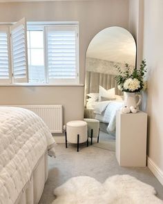 a bedroom with a bed, mirror and white furniture