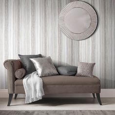 a living room scene with focus on the couch and wall papered walls behind it