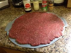 raw ground beef on a blue plate with spices and seasonings in the backround