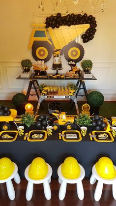 a table topped with yellow and black construction themed desserts on top of a wooden table