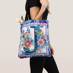 a woman carrying a tote bag with flowers and the letter j on it's side