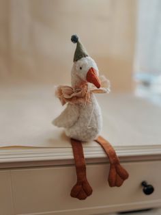 a stuffed duck with a party hat and bow tie sitting on top of a dresser