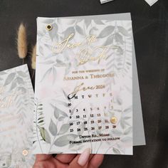 a person holding up two wedding cards with gold foil lettering on the front and back