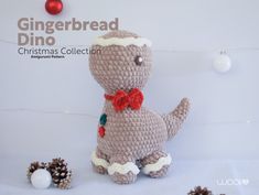 a crocheted dinosaur with a red bow tie sitting next to some pine cones