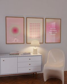 a white chair sitting next to a table with a lamp and two pictures on the wall