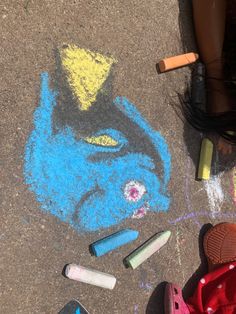 a child's feet and some crayons are on the ground next to chalk