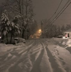 a snow covered street with cars parked on the side and power lines in the background