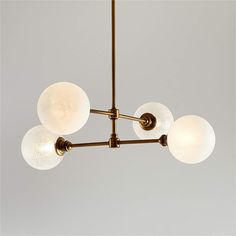 a chandelier with five white glass balls hanging from it's brass frame