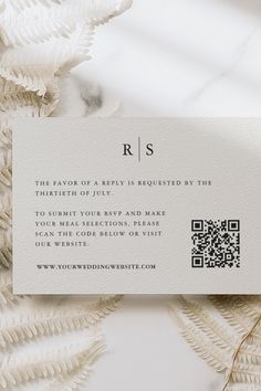 a white business card with a qr code on it sitting next to some feathers