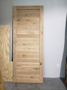 a wooden door sitting in the middle of a room next to plywood planks