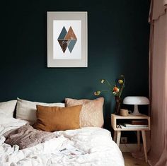 a bedroom with green walls, white bedding and pink curtains on the window sill