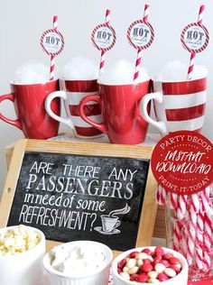 red and white cups with candy canes in them are sitting on a wooden tray