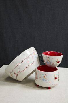 two bowls with fairy tale designs on them sitting next to each other in front of a black background