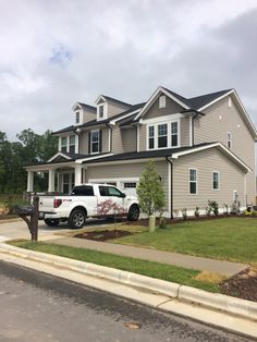 a white truck parked in front of a large gray house with two storyed houses