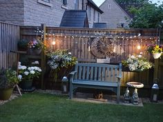 a wooden bench sitting in the middle of a yard next to potted plants and flowers