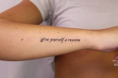 a woman's arm with the words give yourself a reason written on it in cursive font