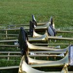 several brass trombones lined up in the grass