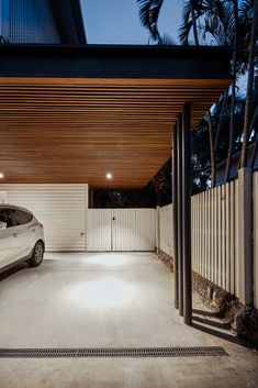 a car is parked in the driveway under a wooden awning over it's entrance