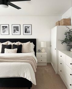 a bedroom with white walls, black and white bedding and pictures on the wall