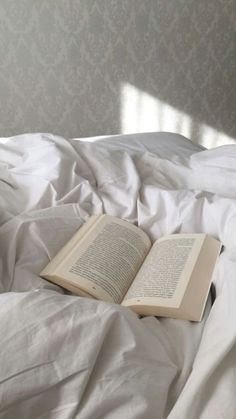 an open book laying on top of a bed