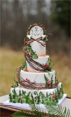 a three tiered cake decorated with greenery and a clock